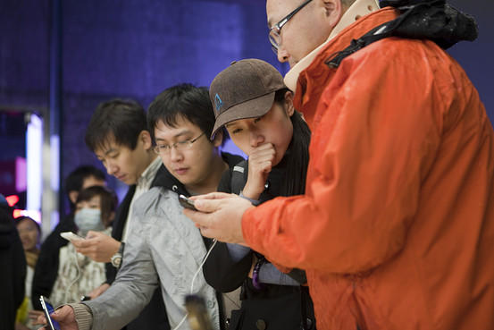 Customers check out the iPhone at a Beijing launch event. (photo: Bloomberg)