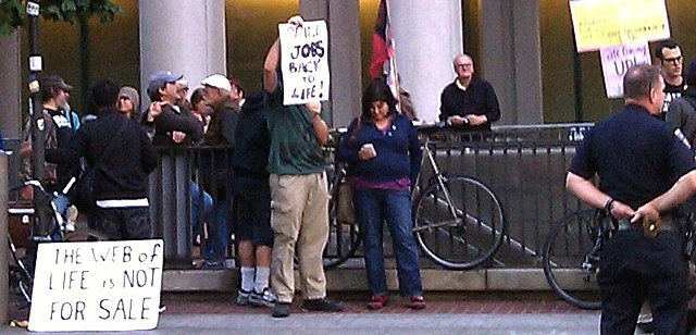 An Occupy Wall Street protester with sign about Steve Jobs in San Francisco.