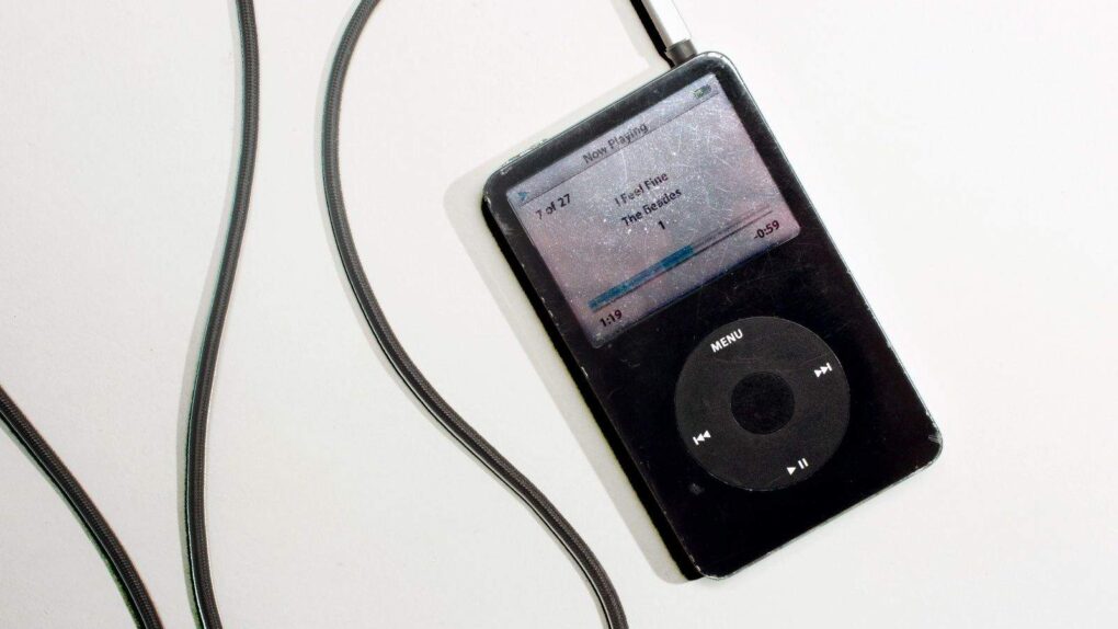 Photograph of a black iPod with a black cord trailing out of it