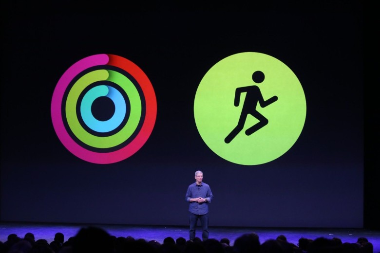 Photo of Apple CEO Tim Cook onstage with Apple Watch icons (Activity rings and running workout) behind him.