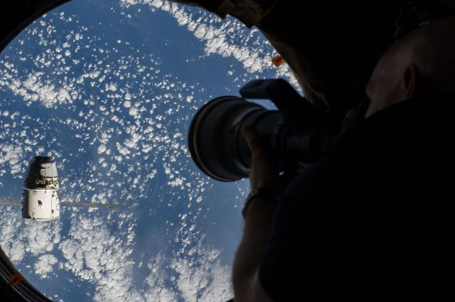 European Space Agency astronaut Alexander Gerst, Expedition 41 flight engineer, uses a still camera at a window in the Cupola of the International Space Station as the SpaceX Dragon commercial cargo craft approaches the International Space Station on Sept. 23. Photo: NASA