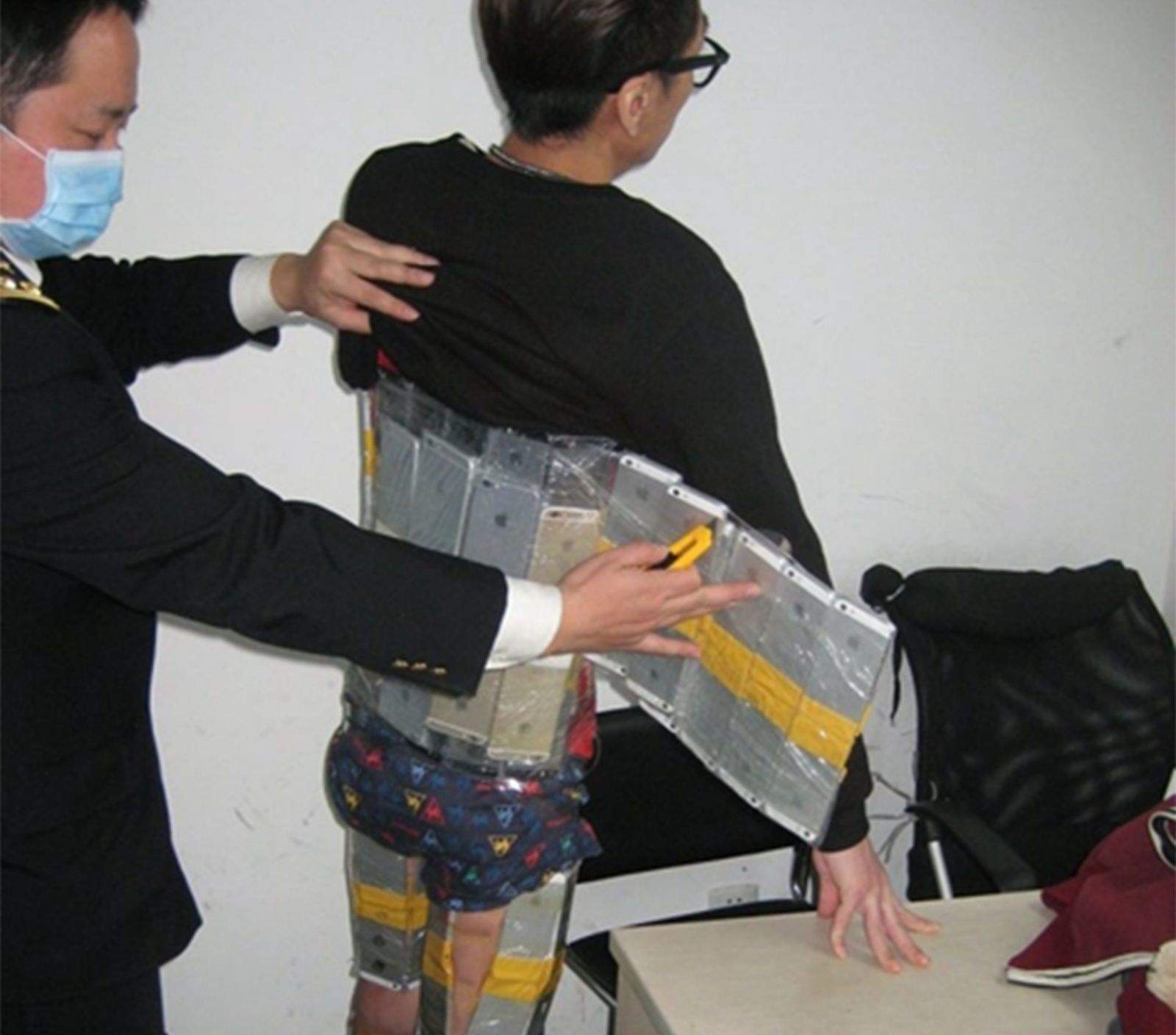 Customs officials in China caught this man trying to smuggle 94 iPhones into the country. Photo: Sina News
