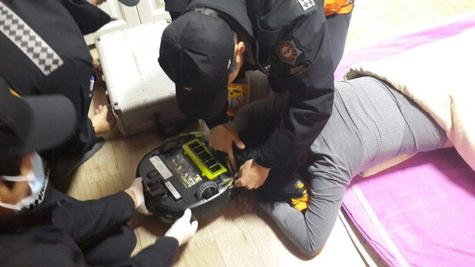 Paramedics work to free a woman from the grips of her robot vacuum. Photo: Changwon Fire Service