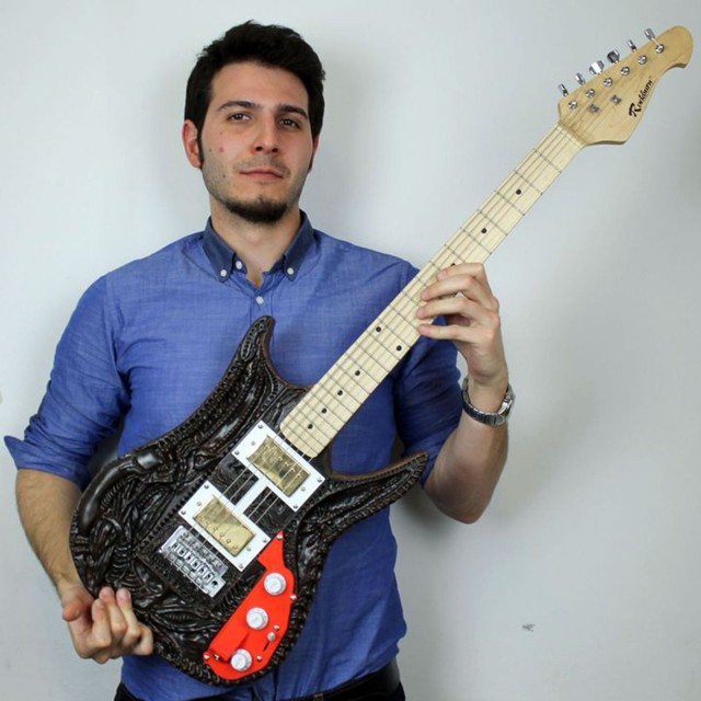 Francesco Orru and his finished guitar that salutes Alien artist H.R. Giger.