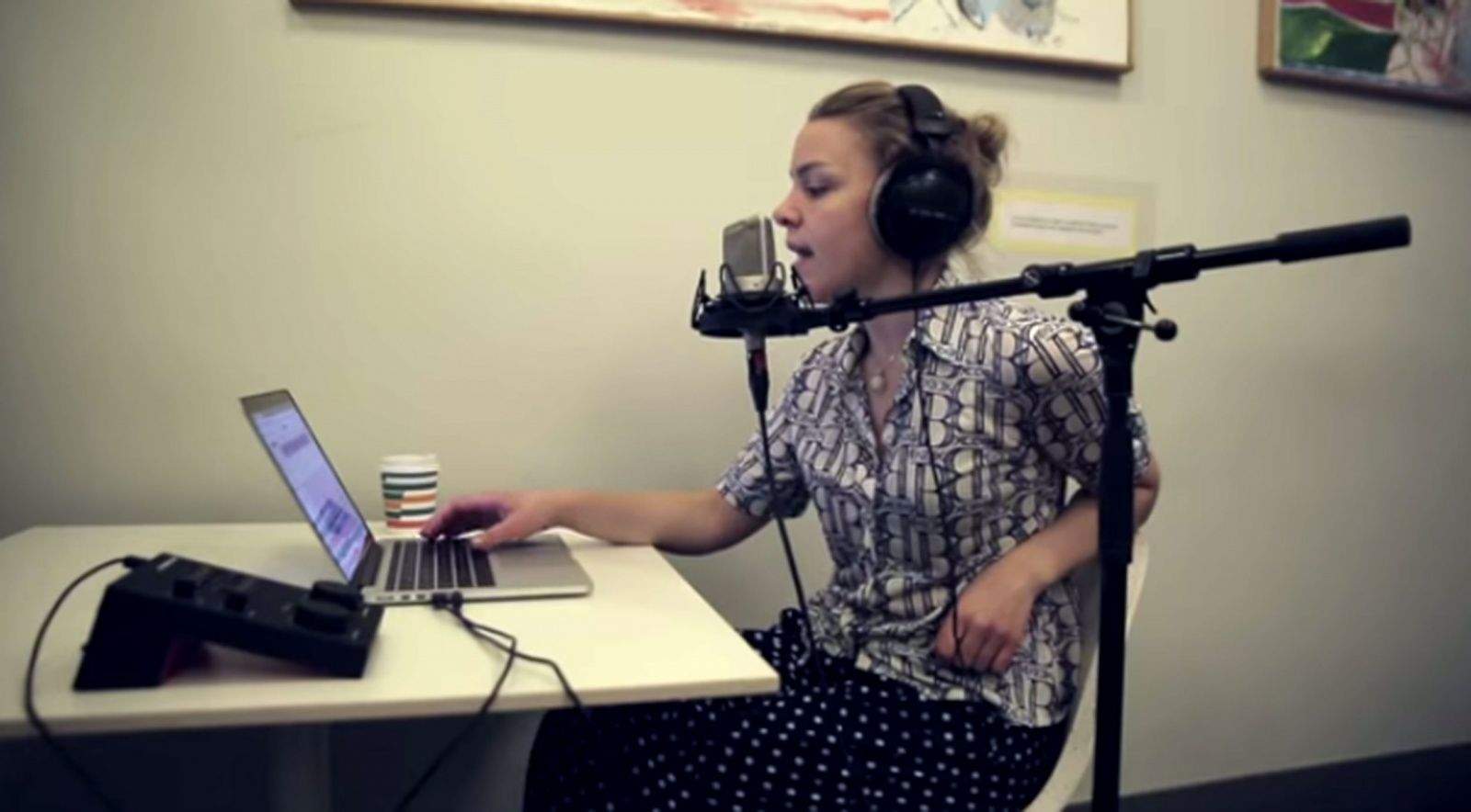 A singer records vocals using Sountrap recording software, which can be used on any device.