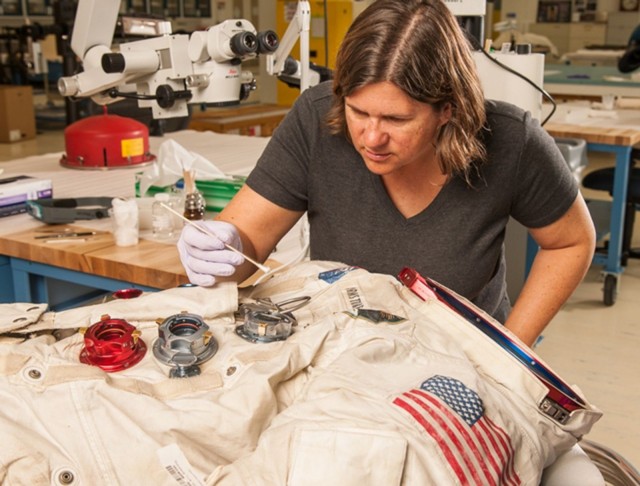 Conservator Lisa Young works on the Armstrong suit.
