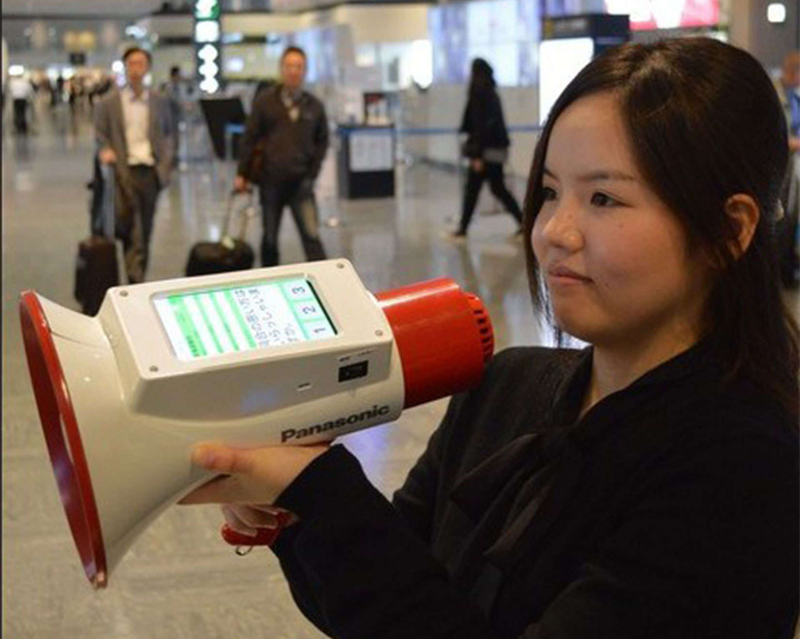 An airport worker holds the Megaphoneyaku, which can broadcast messages in three languages.