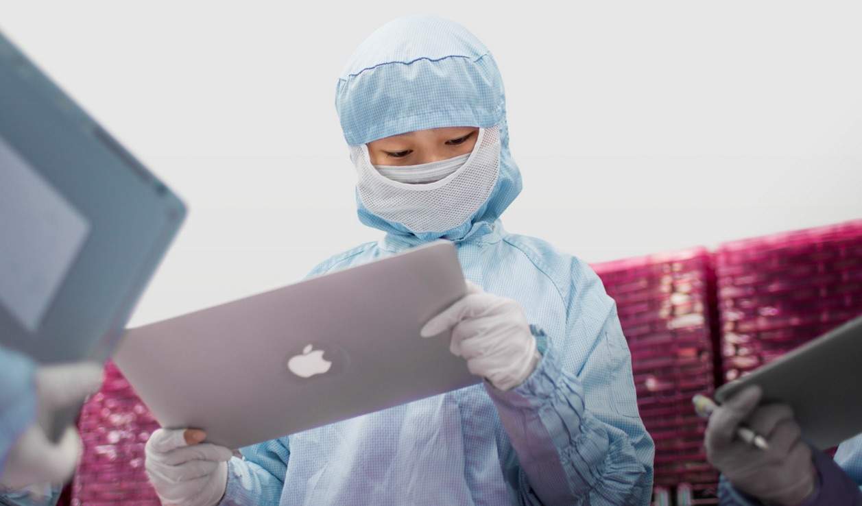 A worker inspecting a MacBook Pro display.