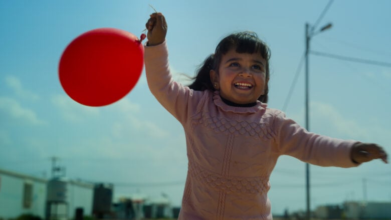 A girl holds a red balloon in a scene from Apple TV+'s adorable and educational docuseries, "Becoming You."