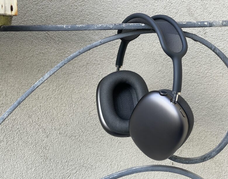 Photo of space gray AirPods Max hanging off a wrought-iron steel hand rail