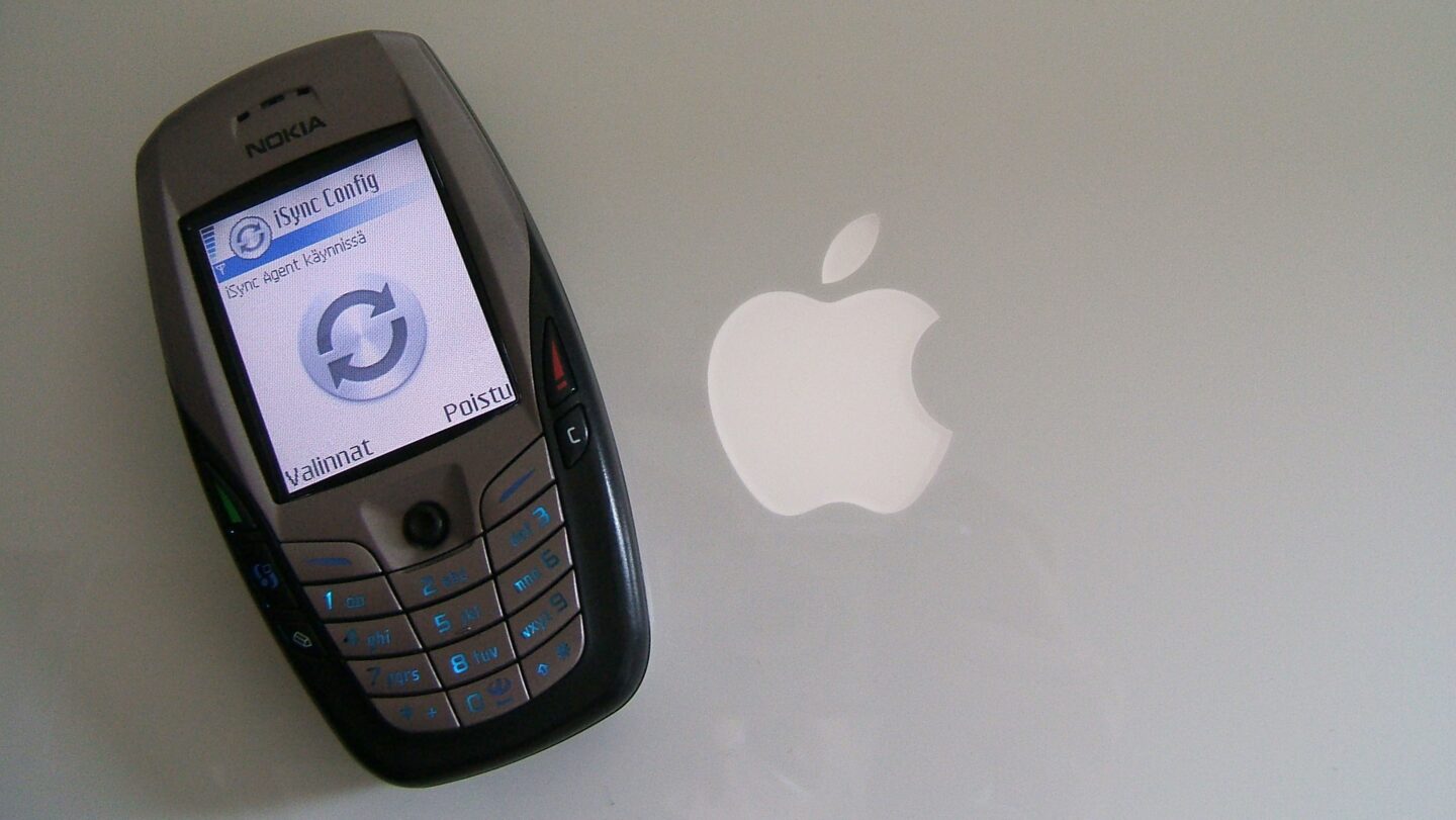 Photo of a Nokia 6600 smartphone on top of a MacBook, used to illustrate a story about Apple's iSync launch.