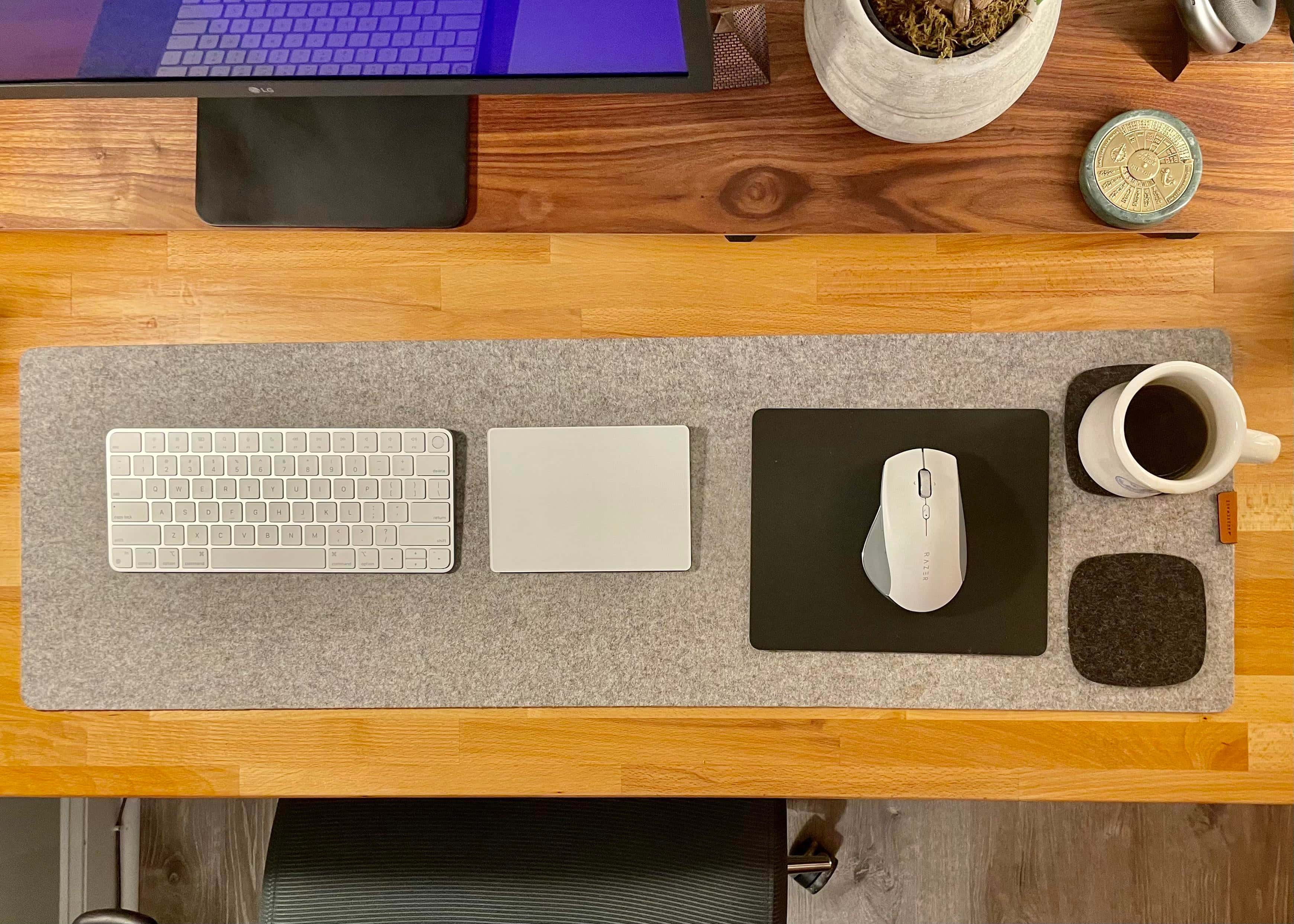 On a Grovemade desk mat, a Magic Keyboard with Touch ID, a Magic Trackpad and a Razer mouse handle input duties.