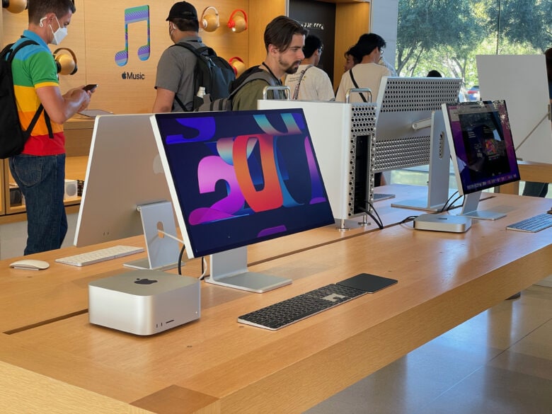 A table of desktop Macs. Going clockwise around the table, starting at the front: the Mac Studio with Studio Display (height-adjustable stand and nano-texture glass), the iMac, Mac Pro with Pro Display XDR (with Pro Stand) and Mac mini with Studio Display (tilt stand).