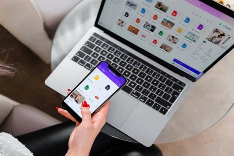 Someone holding an iPhone over a MacBook.