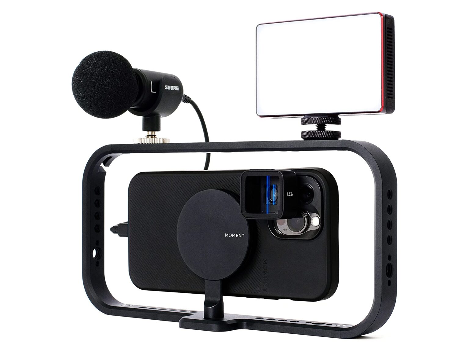 An iPhone with a Moment Case, Anamorphic Lens, and Filmmaker Cage with a microphone and LED light attached.