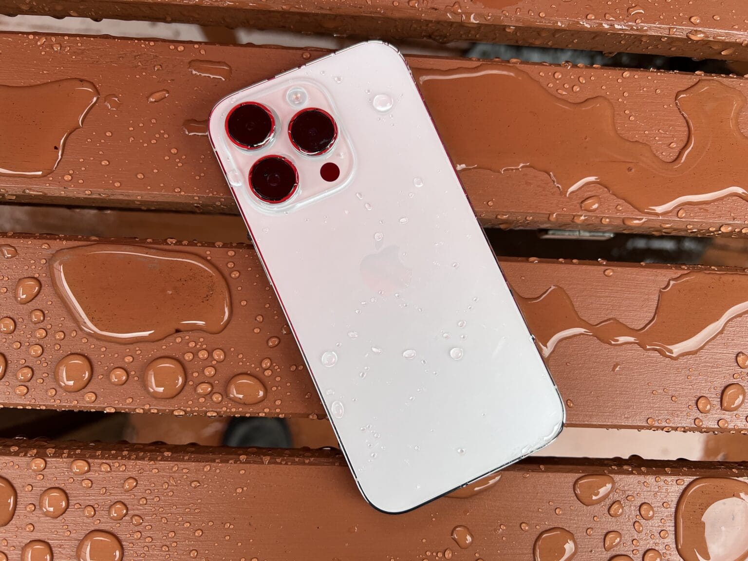 A Silver iPhone 14 on a wet picnic table