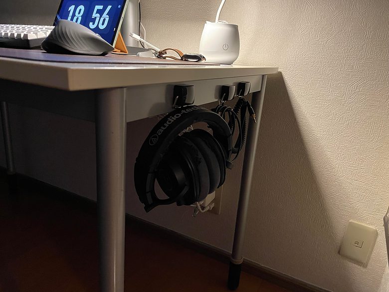 Headphones and cables hang from Daiso hooks, reducing clutter on the desk. 