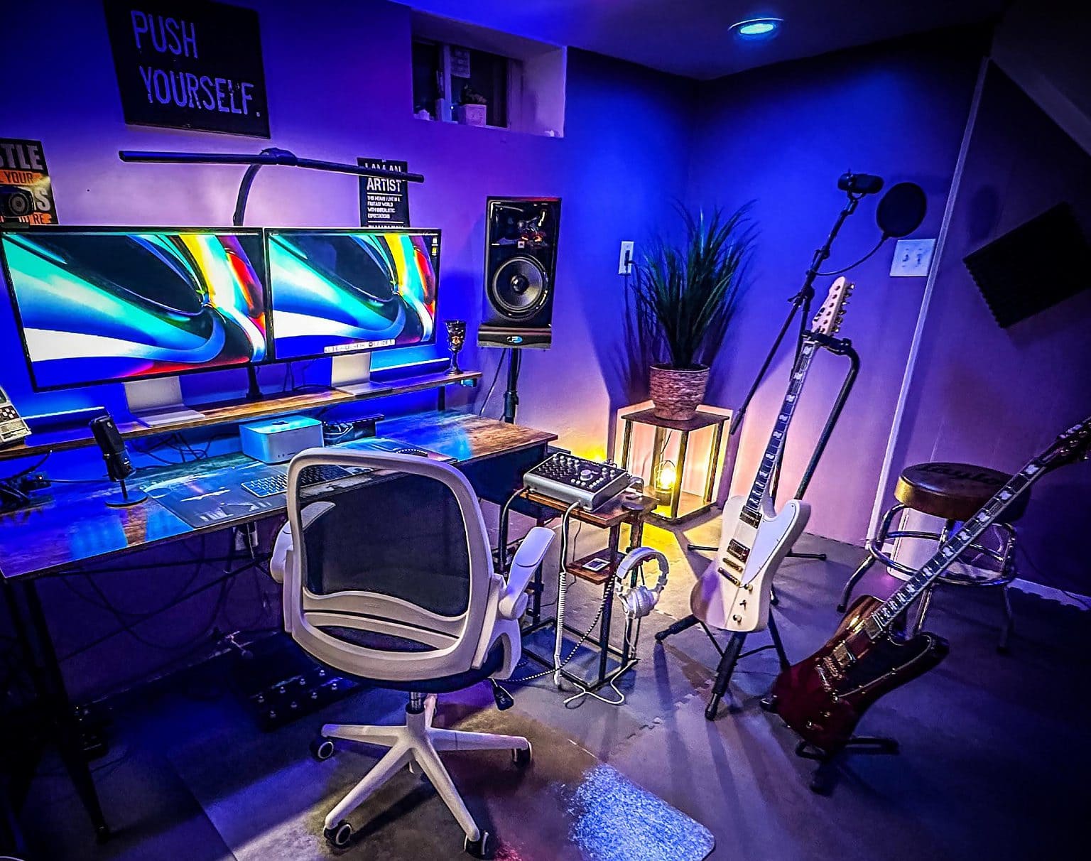 A Mac Studio, two Studio Displays and a whole lot of audio gear and guitars make up this music setup. The Audient iD44 audio interface on the stand in the center of the photograph got replaced with an Apollo X Twin Heritage audio interface.