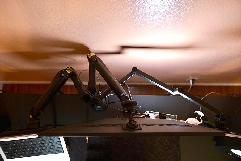A MagSafe car mount hides behind the desk. It flips up to hold an iPhone used as a webcam.