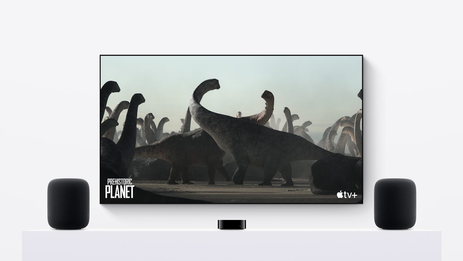 Second-generation HomePods in a stereo pair with an Apple TV 4K and a giant TV screen showing Apple TV+ dinosaur documentary 