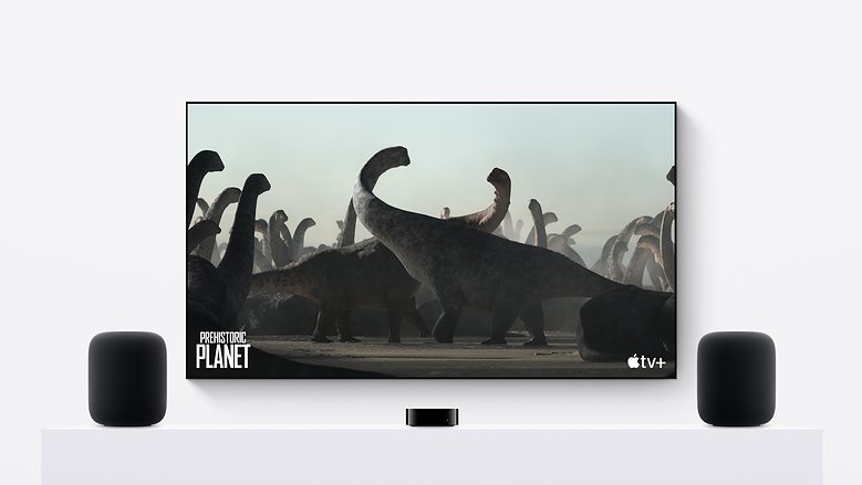 Second-generation HomePods in a stereo pair with an Apple TV 4K and a giant TV screen showing Apple TV+ dinosaur documentary "Prehistoric Planet."