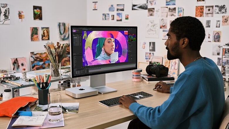 A man editing video in Premiere Pro with a new Mac mini and a Studio Display