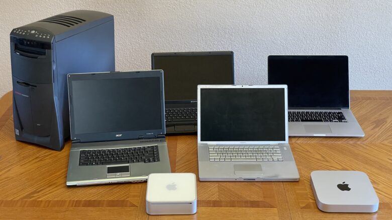 A whole bunch of Macs and ugly old PCs sitting on a table