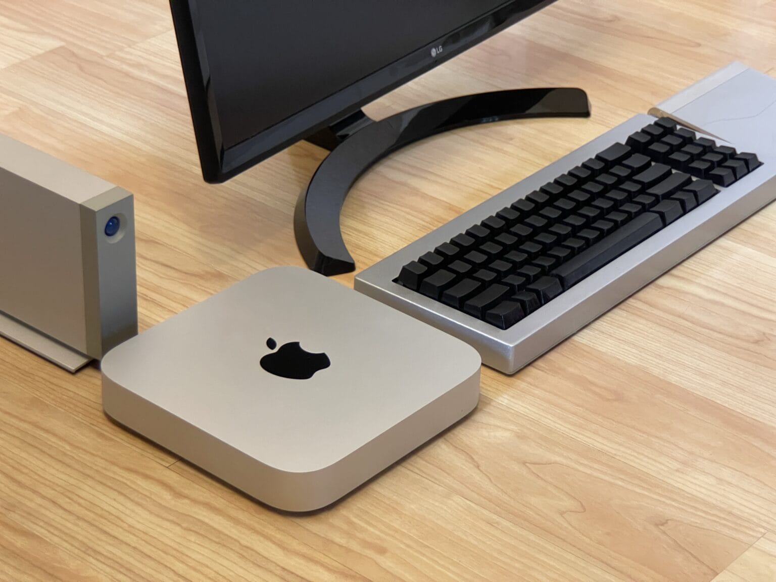 Mac mini with external hard drive, keyboard, trackpad and display sitting on the floor (isometric perspective)