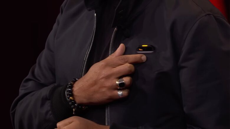 Imran Chaudhri pointing to the Humane badge device pinned to his shirt.
