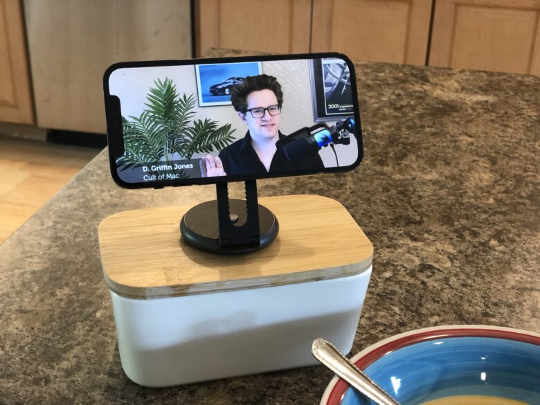 iPhone mounted on SwitchEasy Orbit sitting on a butter dish on a kitchen island. An empty bowl with a spoon is sitting in front of it to imply lunch is happening.