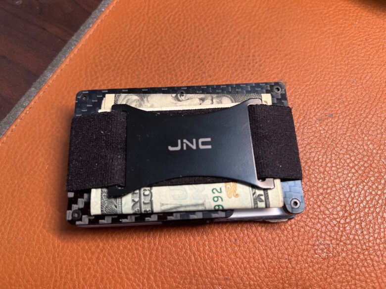 My carbon-fiber wallet holds cash on the outside and up to about 10 cards on the inside. But it doesn't stick to my iPhone.