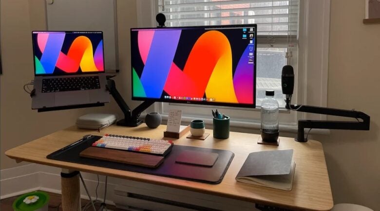 A dual monitor mount is used for the external display and the MacBook Pro.