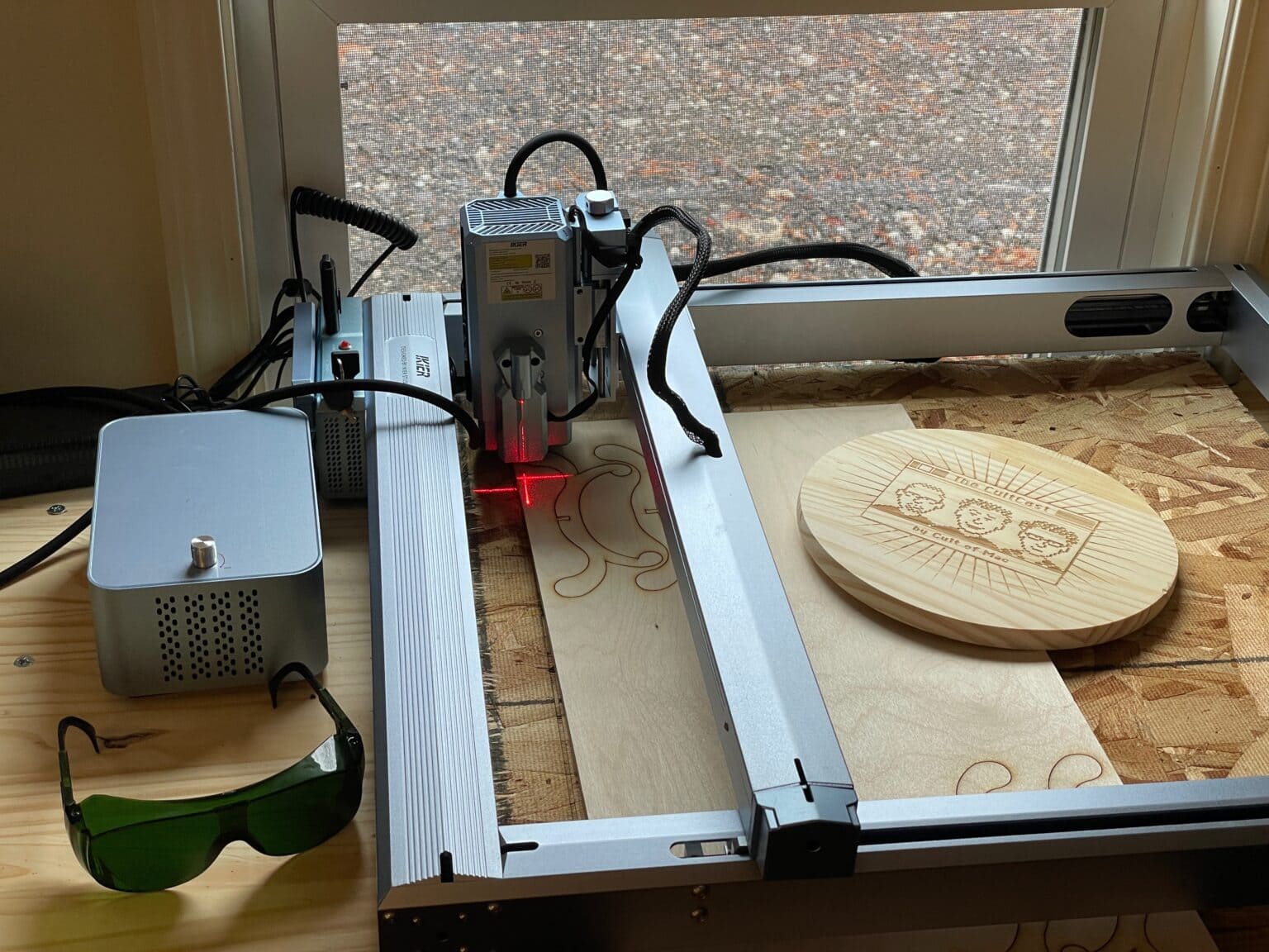 iKier K1 Pro Max laser engraver with a few projects etched into wood sitting beside it
