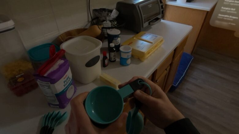 Holding up a measuring cup, seemingly with no visible label.