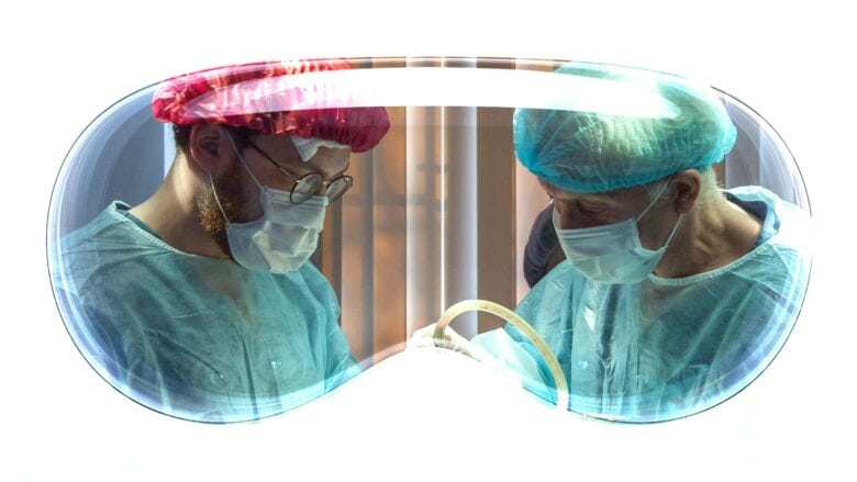 Apple Vision Pro headset overlaid atop photo of two surgeons.