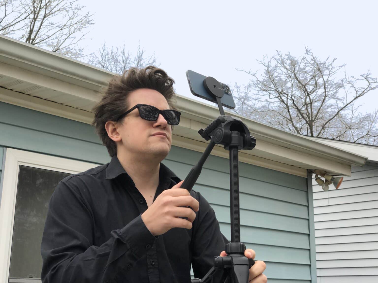 Person wearing sunglasses taking a picture on an iPhone on a tripod