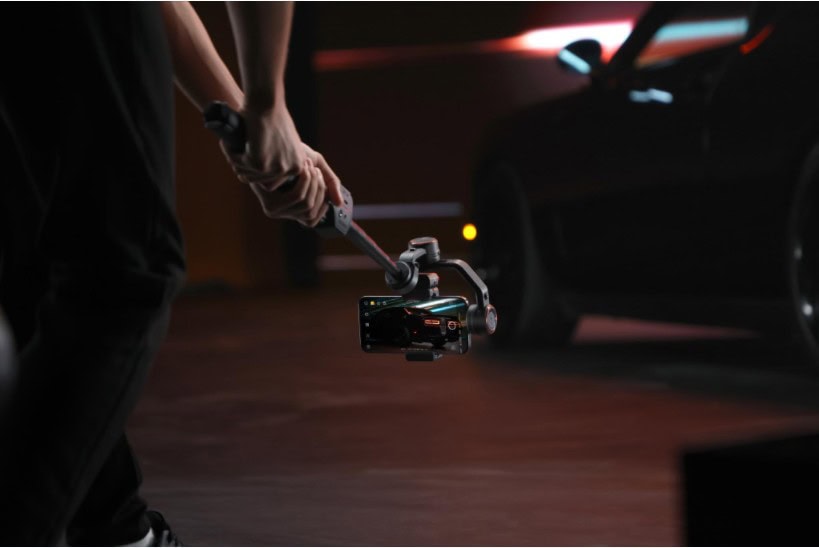 Photograph shows person using Hohem iSteady M7 gimbal for phone to capture a low shot