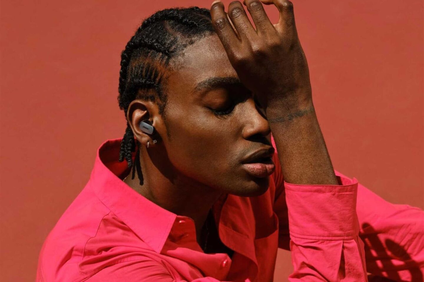 Man in pink shirt wearing Bose QuietComfort Ultra earbuds.