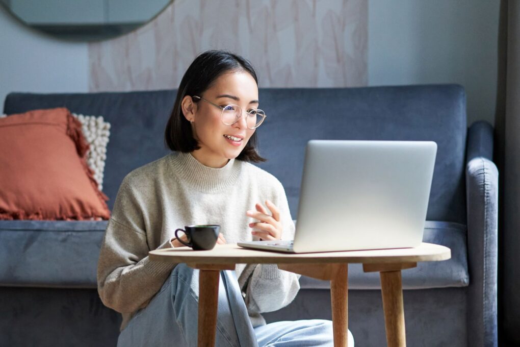 A woman sitting on the floor and looking at her laptop while using AI screen recorder Canvid.