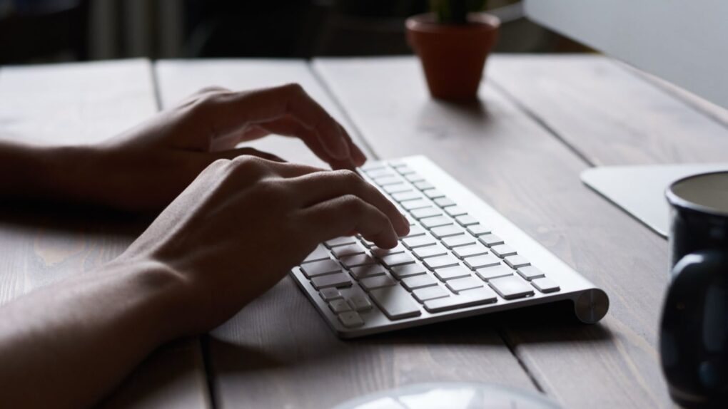 Photo of a person typing on an Apple keyboard using Mac keyboard shortcuts