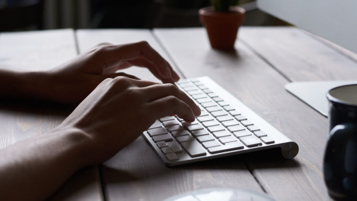 Photo of a person typing on an Apple keyboard using Mac keyboard shortcuts