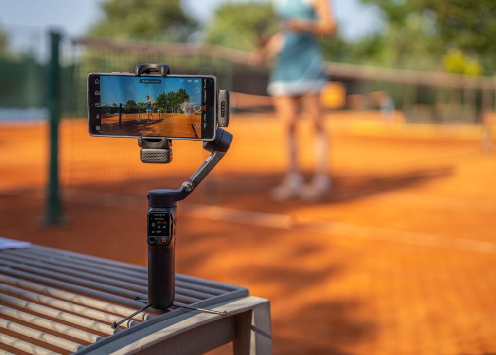 Photo of the Hohem iSteady V3 Ultra phone gimbal sitting on a bench, to capture video of a tennis match
