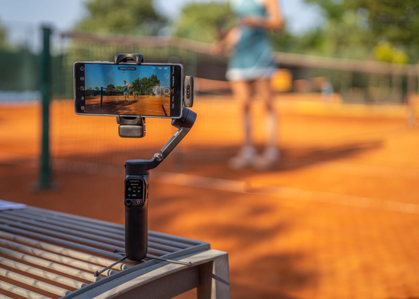 Photo of the Hohem iSteady V3 Ultra phone gimbal sitting on a bench, to capture video of a tennis match