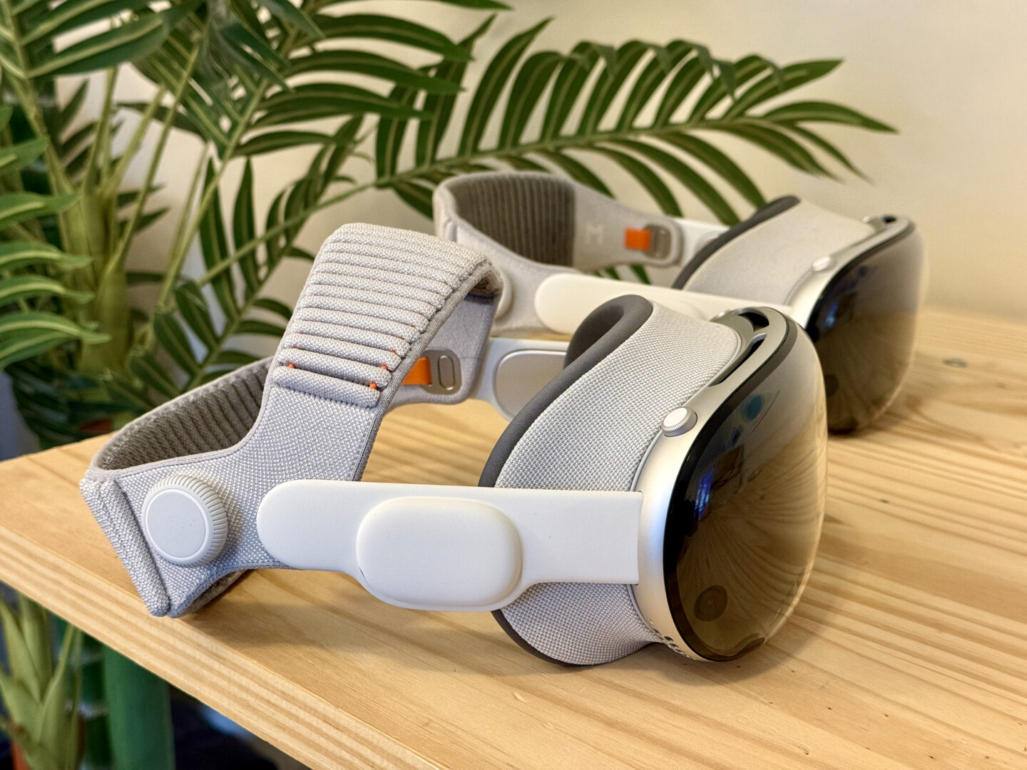 M5 M2 Vision Pro Comparison M5 and M2 Vision Pro sitting side by side in front of a fake palm tree.