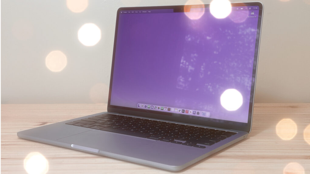Photo of an M4 MacBook Air sitting on a desk with lights glinting off it, used to illustrate a guide to best Mac utilities.