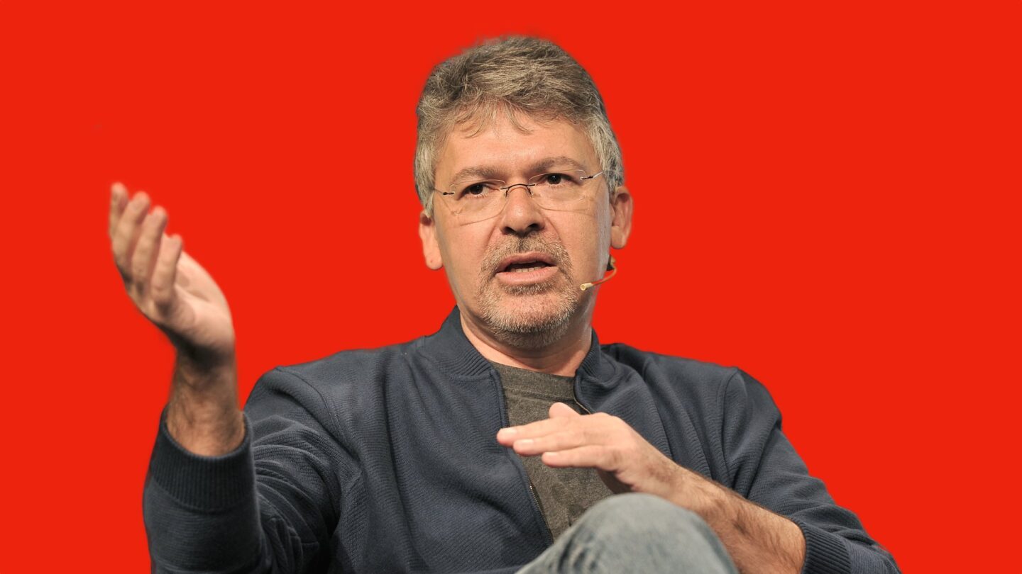 Photo of John Giannandrea, Apple’s senior vice president for Machine Learning and AI Strategy, with a bright red background