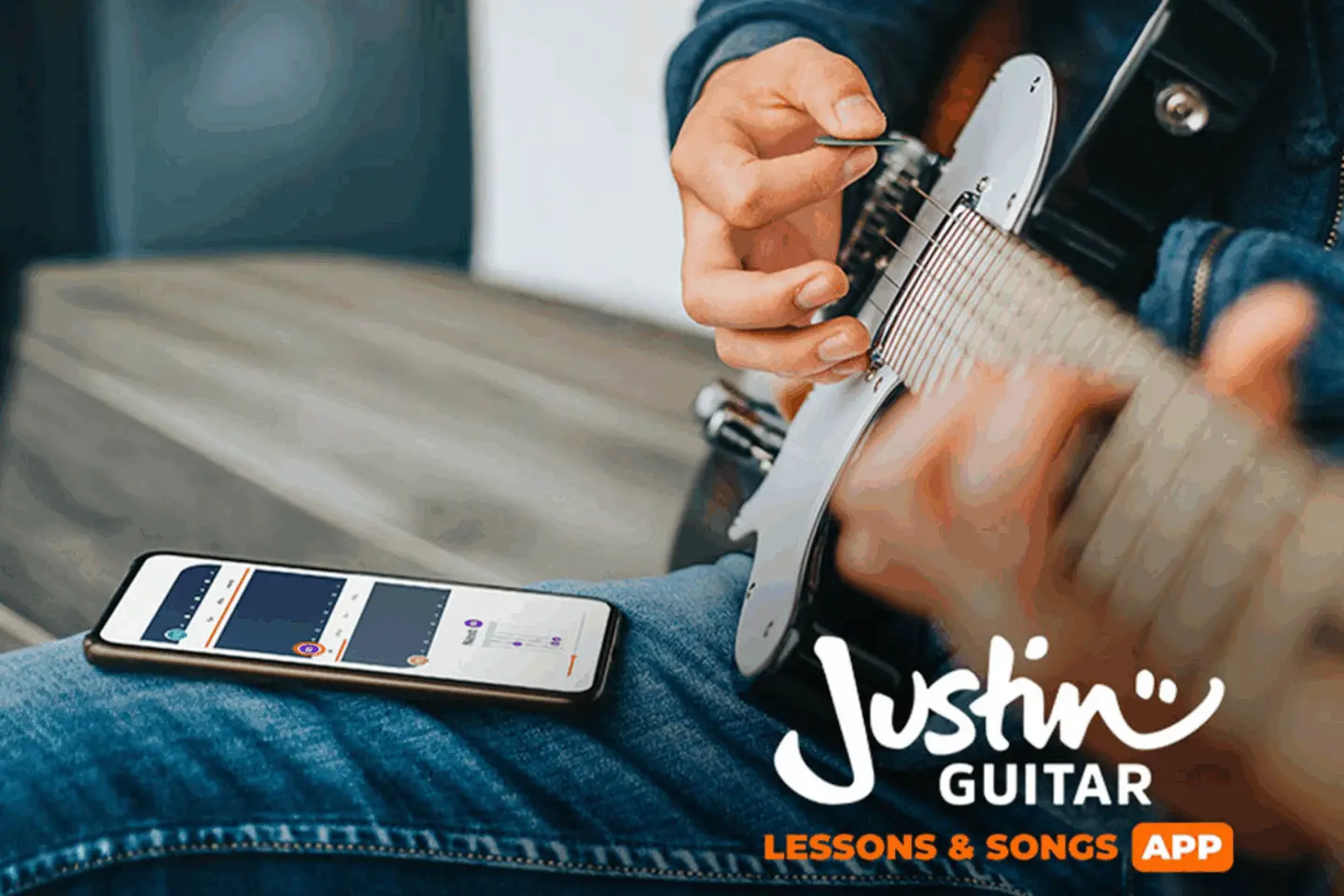 Photo of a person playing a guitar on a couch with the JustinGuitar log