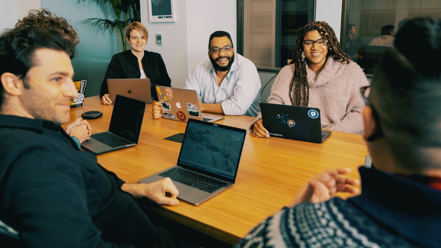 Photo of people working around a desk using Apple laptops, used to illustrate a story about Apple computers used i business
