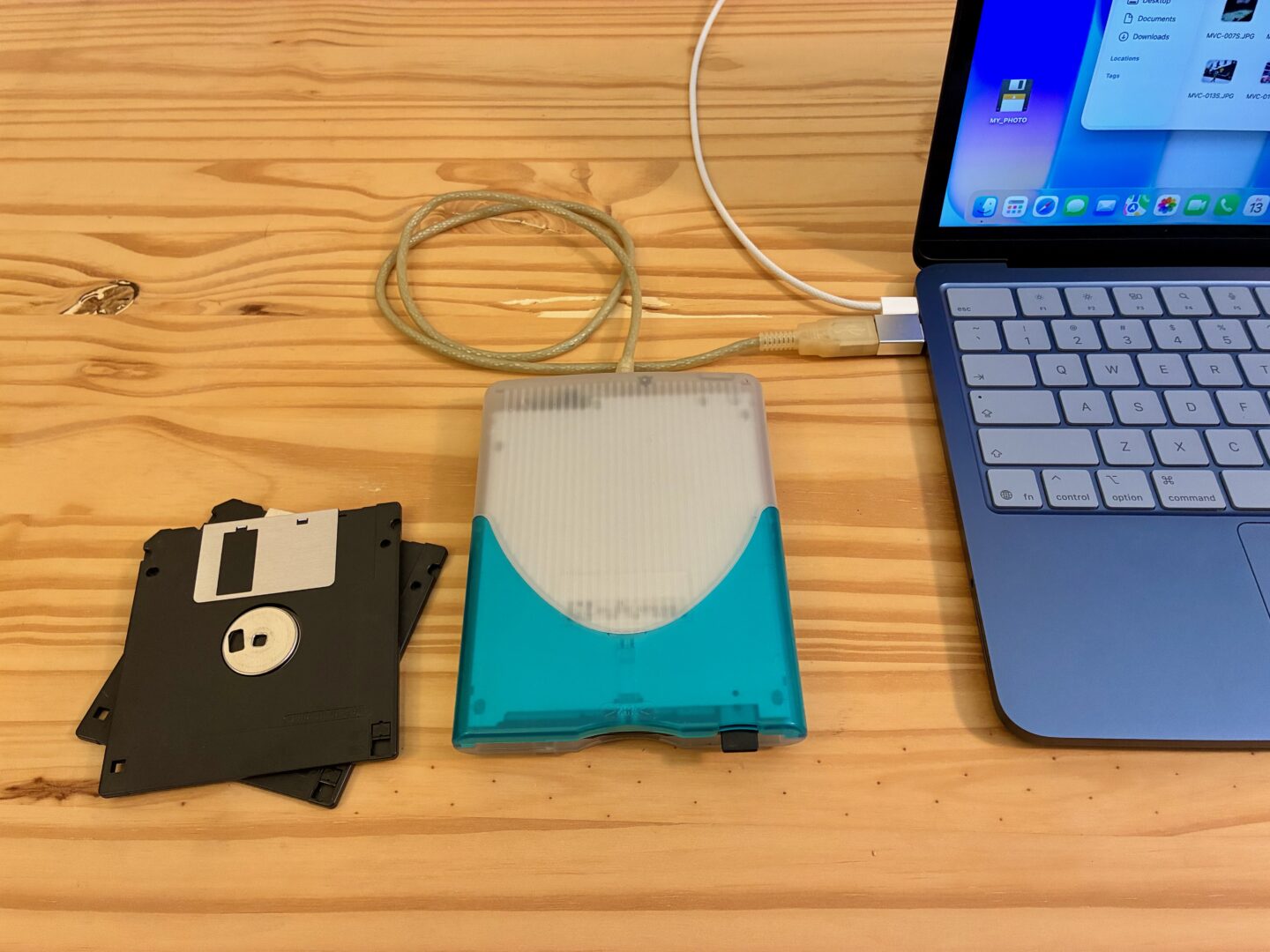 MacBook Neo in Indigo with an old USB floppy disk drive plugged in.