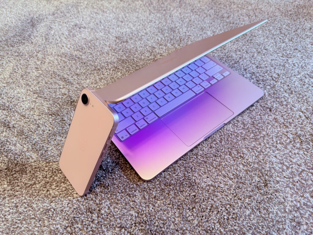 Pink iPhone 17e with the pink MacBook Neo sitting on a gray carpet
